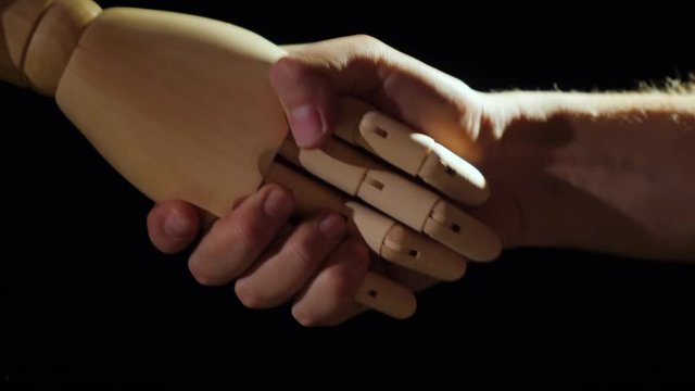 Human and Android handshake on black background