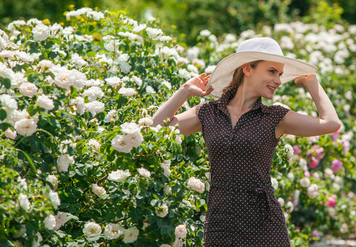 Beautiful woman in retro style polka dot dress and hat in Bulgarian rose garden.