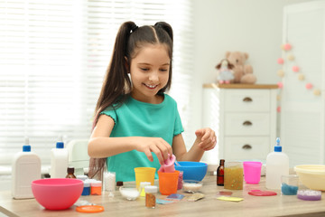 Obraz na płótnie Canvas Cute little girl making DIY slime toy at table indoors
