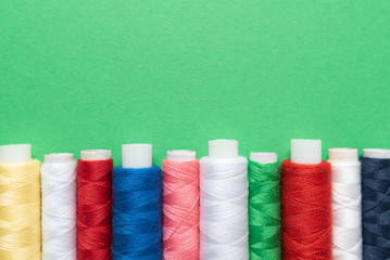 colored sewing threads on green background
