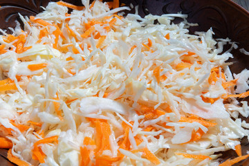 Fototapeta premium Grated cabbage and carrots in a ceramic bowl close-up