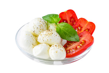 Caprese salad isolated on white background. Mini mozzarella cheese balls with basil and red cherry tomatoes in a glass bowl. Mediterranean cuisine.