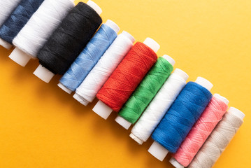 colored sewing threads on yellow background