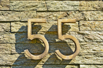 A house number plaque, showing the number fifty five (55)