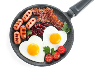 Delicious breakfast with heart shaped eggs and sausages isolated on white, top view