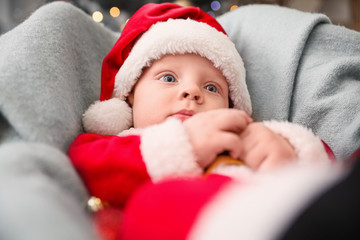 Cute little baby in Santa Claus costume at home