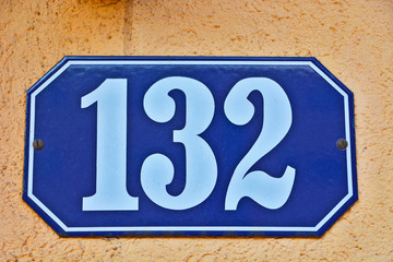 A house number plaque, showing the number one hundred thirty two (132)