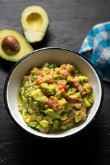 Mexican guacamole with tomato on dark  background