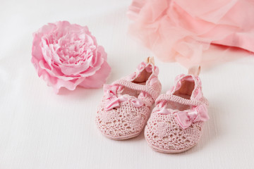 Children's shoes with clothes and a flower on a light background.