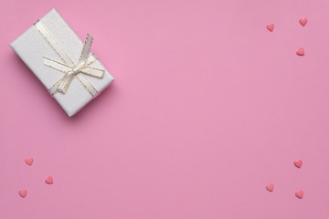..Romantic concept for Valentine`s Day. Flat lay. Pattern of pink hearts on a pink background and white gift box. Copy Space.