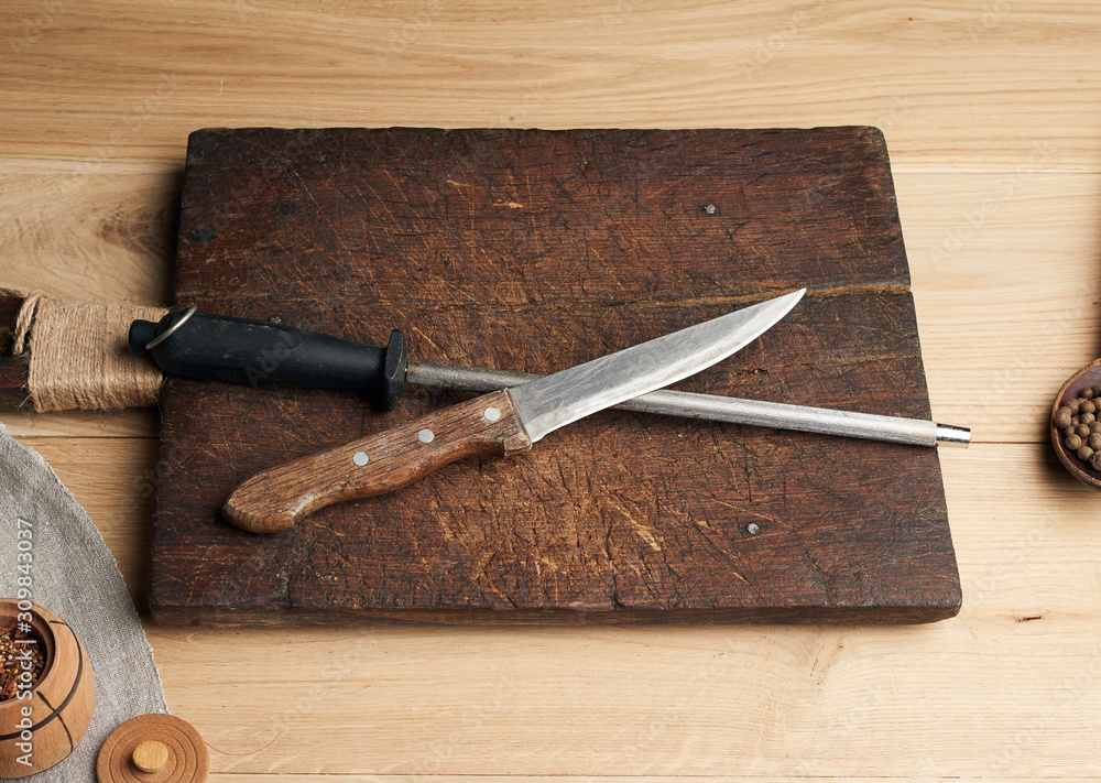 Poster old sharp knife and sharpener with a handle on a wooden background