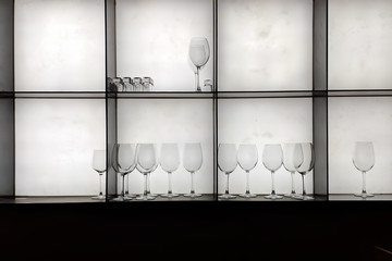 Rack with transparent glasses for various alcohol in the bar. On white background.