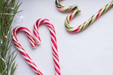 Christmas candy in the form of hearts on a white background, with a fir branch and New Year's lights, there is a free place for recording, top view