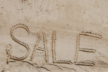 The word sale is painted on the sand. Beach background. View from above. The concept of summer, summer kanikkuly, vacation, holydays.