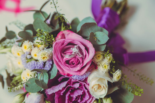 coloured macro photo of a detailed bouquet with pink roses, white small flowers and a fake diamond in the centre of the rose