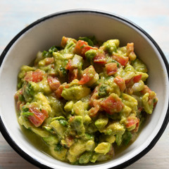 Mexican guacamole with tomato on wooden  background