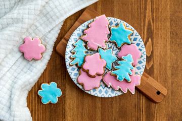 Fototapeta na wymiar Home-cooked ginger christmas cookies with pink and blue sugar icing on a plate. Warm home baking