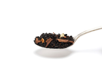 Dry leaves of black fruit tea with orange and cinnamon on a spoon. Isolate on a white background.