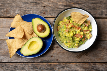 Mexican guacamole with tomato on wooden background
