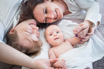 Fototapeta na wymiar Top view happy positive Young family husband wife and little newborn baby lie on a cozy bed. Concept of a long-awaited child and child care