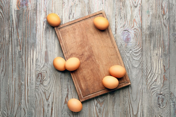 Board with fresh eggs on wooden background