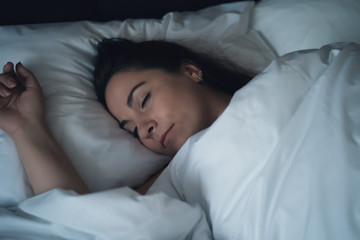 Young beautiful girl or woman sleeping alone in big bed at night.