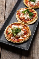 Mexican sopes with red sauce and fresh cheese on wooden background