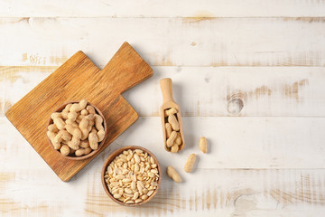 Tasty peanuts on white wooden background