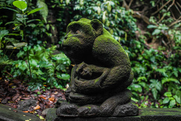 Sculpture mom monkey with a cub in a Bali park. Monkey forest.