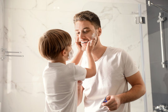 Dad and son with shaving foam on their faces having fun in bathroom - Powered by Adobe