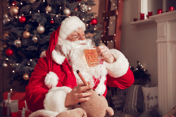 Funny Santa Claus drinking beer and smoking cigar at home