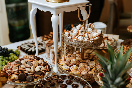 Wedding candybar with desserts, creamy and colorful pastries, delicious cookies, ananas, macarons, muffins