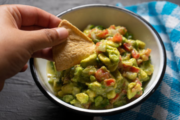 Mexican guacamole with tomato on dark  background