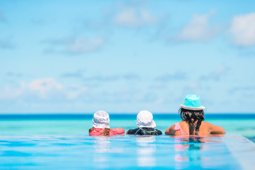 Mother and two kids enjoying summer vacation in luxury swimming pool