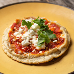 Mexican sopes with red sauce and fresh cheese on wooden background