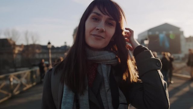 Lifestyle portrait of happy beautiful smiling young woman posing for camera at sunset autumn Paris square slow motion.