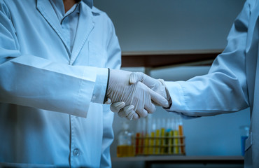 Scientists shake hands together to symbolize research and experimentation together