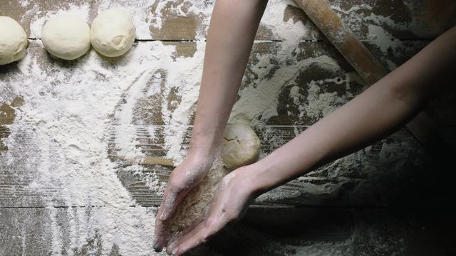 baker makes ball of fresh dough on table view from above