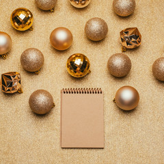 Craft notebook with Christmas decorations on gold background.