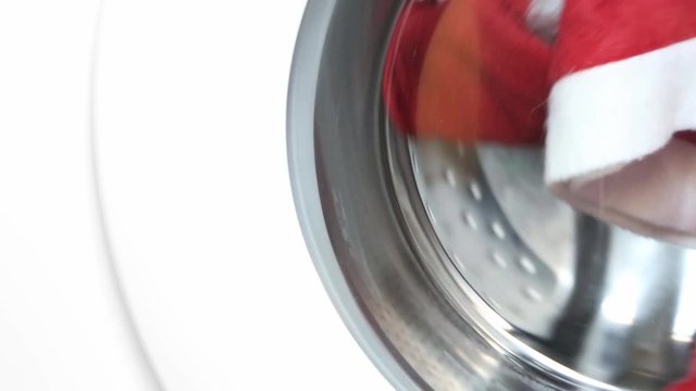 Red Santa Claus' costume washing in the washing machine. Father Christmas doing the laundry and is getting ready for the Christmas holidays.