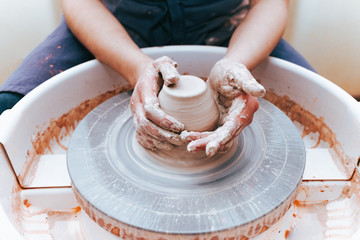 Process of creating and formation a white clay ceramic plate. Professional potter is engaged in modeling clay plates. Potter works in a workshop