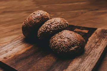 Cereal bread lie on a wooden table with a cutting board.