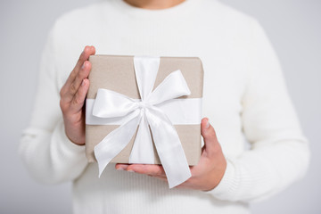 close up of wrapped gift box in male hands over gray background