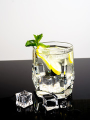 Vodka with lemon and ice on a black background - 309851203