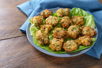 Fried shrimp snacks with garlic and spring onions, finger food appetizer for a festive menu, blue plate and napkin, dark rustic wooden table with copy space