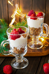 Christmas dessert, strawberry mousse with yogurt, cornflakes and fresh berries, vertical image, wooden table with holiday illumination