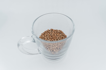 Buckwheat in a transparent glass on a white background