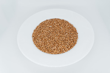 Buckwheat in a plate on a white background close-up