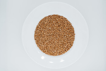 Buckwheat in a plate on a white background close-up