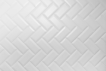 Beveled white matt ceramic tiles pattern herringbone on wall.